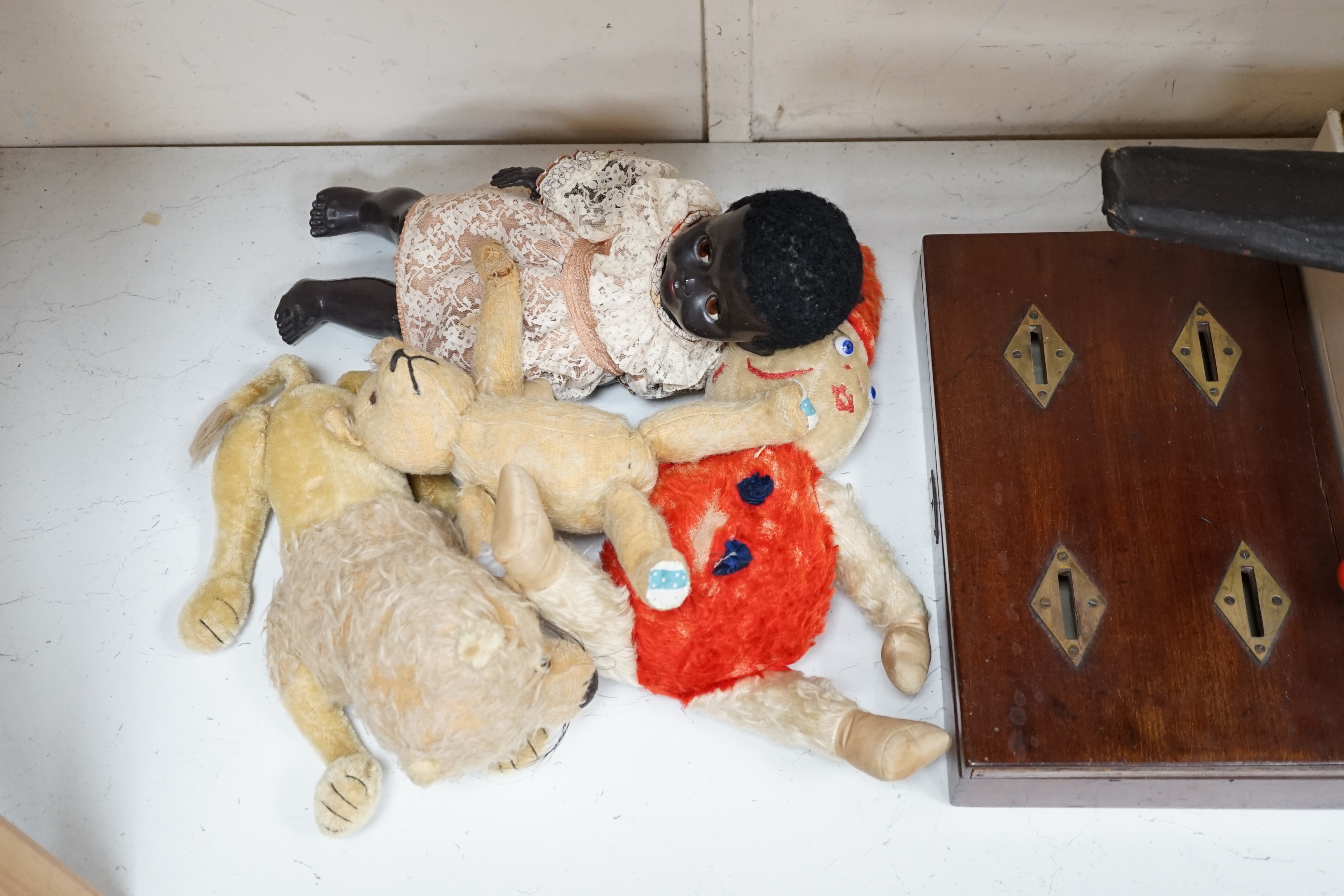 An early 20th century cased Bussey’s Hawk kite, a black walkie talkie doll, a four slot money box, an early Pelham puppet and two others, a hump backed teddy, together with various games and soft toys